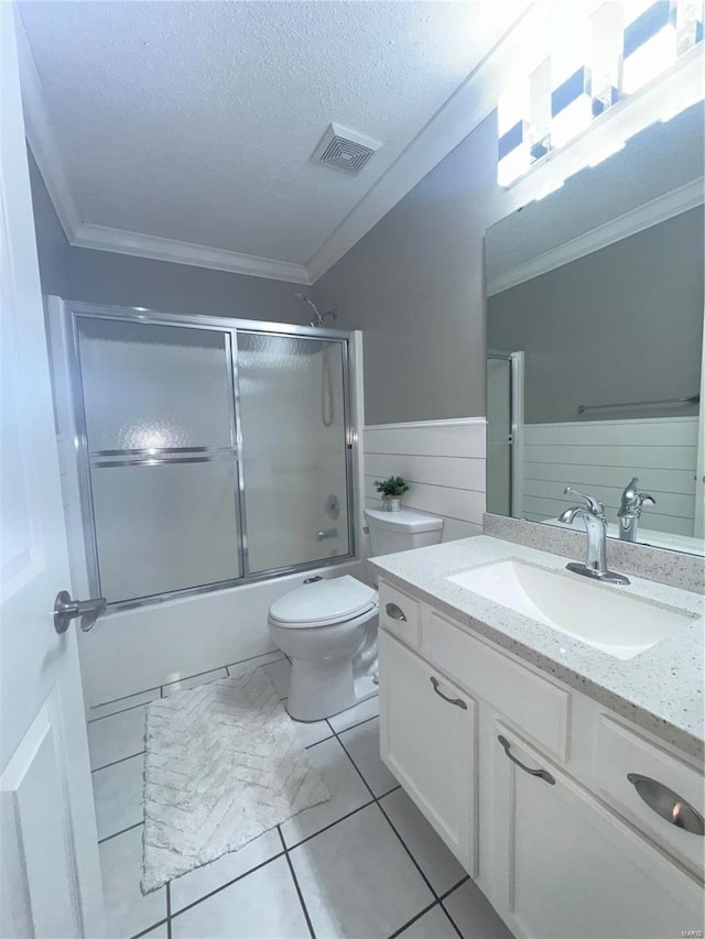 full bathroom featuring visible vents, a textured ceiling, a wainscoted wall, and ornamental molding