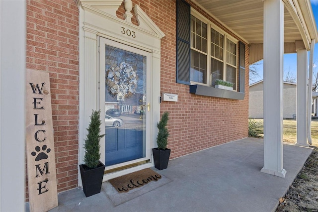 property entrance featuring brick siding and covered porch