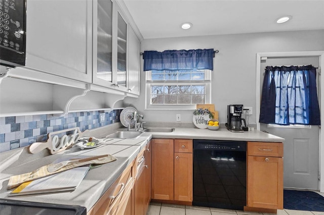 kitchen featuring backsplash, black dishwasher, light tile patterned flooring, light countertops, and glass insert cabinets