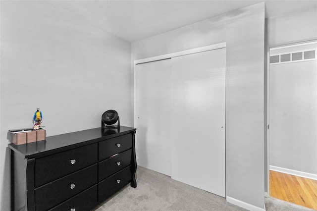 bedroom with visible vents, light colored carpet, and a closet