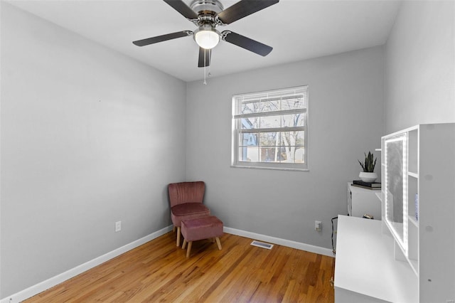 living area featuring visible vents, baseboards, light wood-style flooring, and a ceiling fan