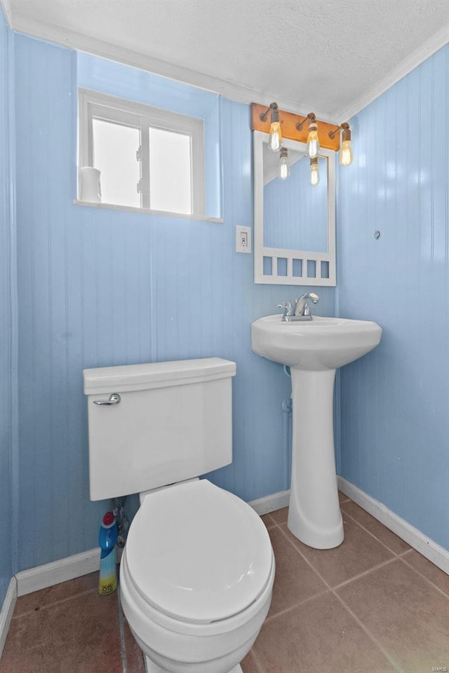 bathroom featuring tile patterned flooring, a textured ceiling, toilet, and baseboards