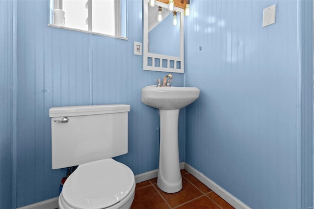 bathroom with baseboards, toilet, and tile patterned flooring