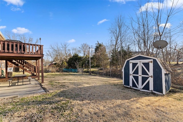 view of yard with a storage unit, an outbuilding, a fenced backyard, stairway, and a wooden deck