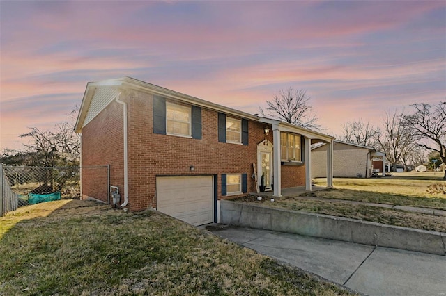 view of front facade featuring brick siding, fence, concrete driveway, a yard, and an attached garage