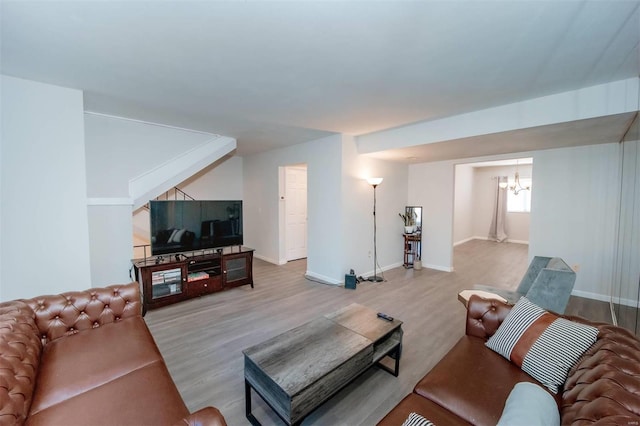 living area with baseboards, wood finished floors, and a notable chandelier