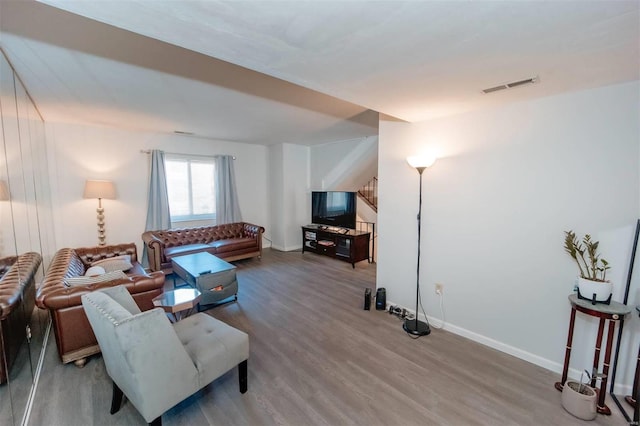 living area featuring visible vents, baseboards, and wood finished floors