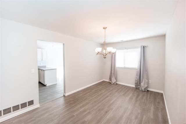 unfurnished room featuring a chandelier, baseboards, visible vents, and light wood-style floors