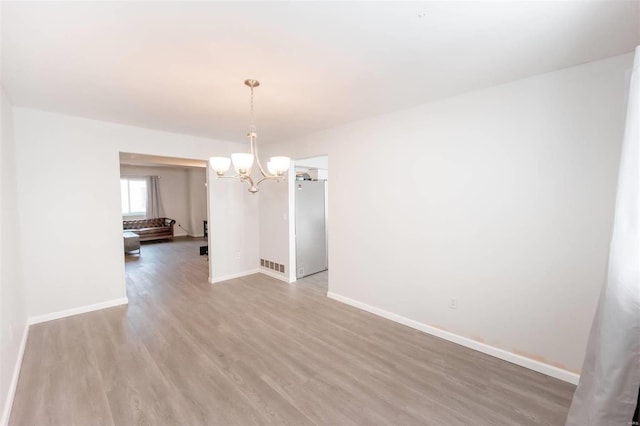 unfurnished dining area featuring an inviting chandelier, light wood-type flooring, visible vents, and baseboards