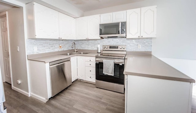 kitchen featuring light wood finished floors, tasteful backsplash, appliances with stainless steel finishes, white cabinets, and a sink