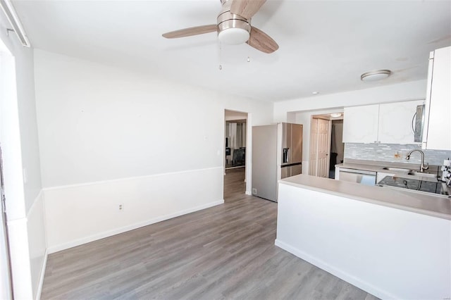 kitchen with tasteful backsplash, appliances with stainless steel finishes, light wood-style floors, white cabinetry, and a sink