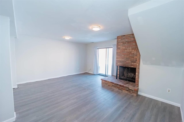 unfurnished living room with a fireplace, baseboards, and wood finished floors