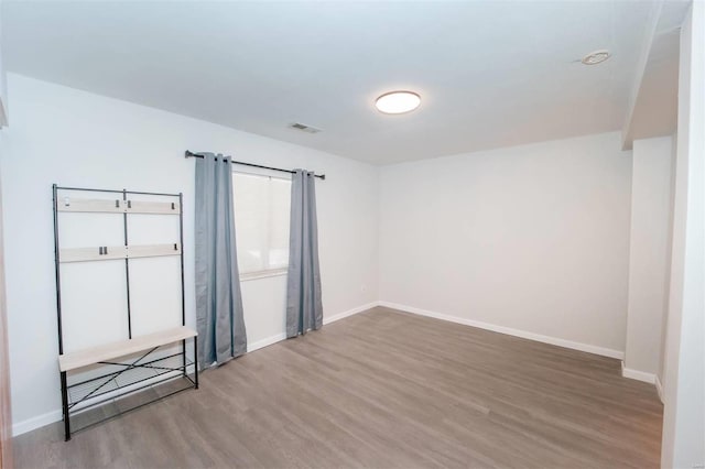 unfurnished room featuring wood finished floors, visible vents, and baseboards