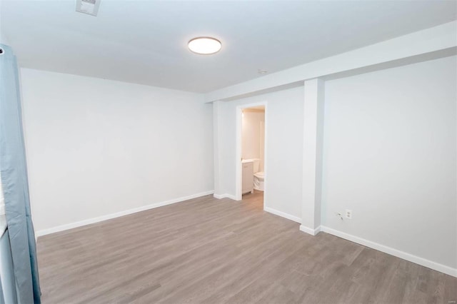 spare room featuring wood finished floors, visible vents, and baseboards