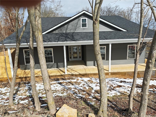 view of front of home with a shingled roof, a patio area, and fence