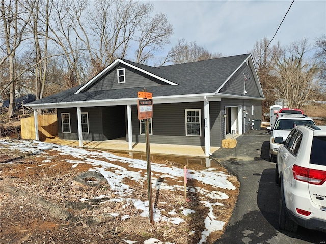 view of front of property featuring central AC unit, a porch, and roof with shingles