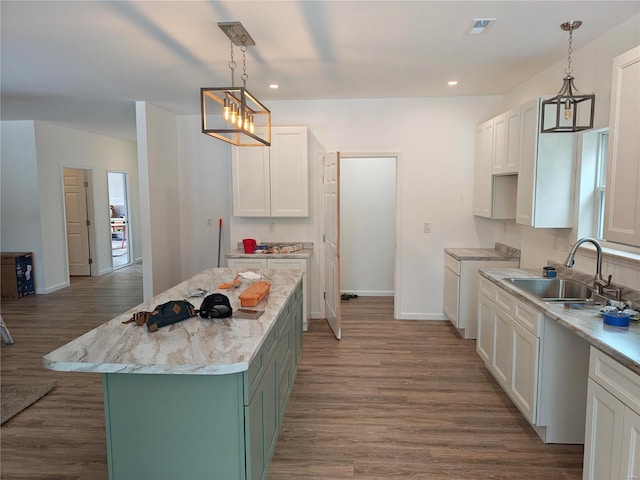 kitchen featuring white cabinetry, a sink, baseboards, and wood finished floors