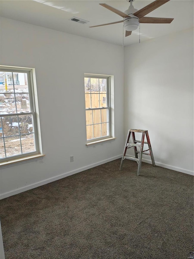 unfurnished room featuring ceiling fan, baseboards, visible vents, and dark colored carpet