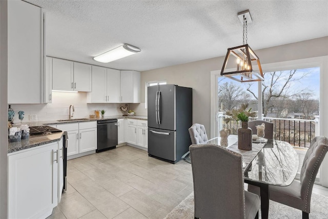 kitchen with a sink, white cabinets, appliances with stainless steel finishes, backsplash, and dark stone counters