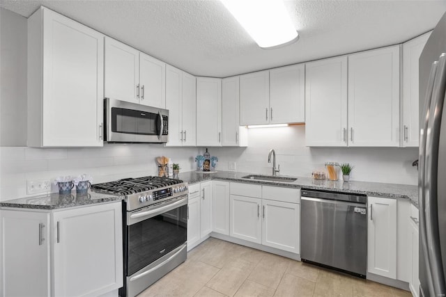 kitchen with appliances with stainless steel finishes, a sink, and white cabinetry