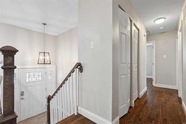 interior space featuring baseboards, a textured ceiling, an upstairs landing, and wood finished floors