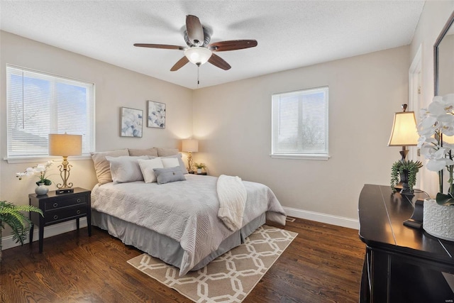 bedroom featuring ceiling fan, dark wood-type flooring, multiple windows, and baseboards