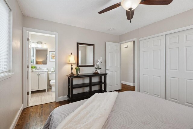 bedroom with connected bathroom, a sink, baseboards, a closet, and dark wood-style floors