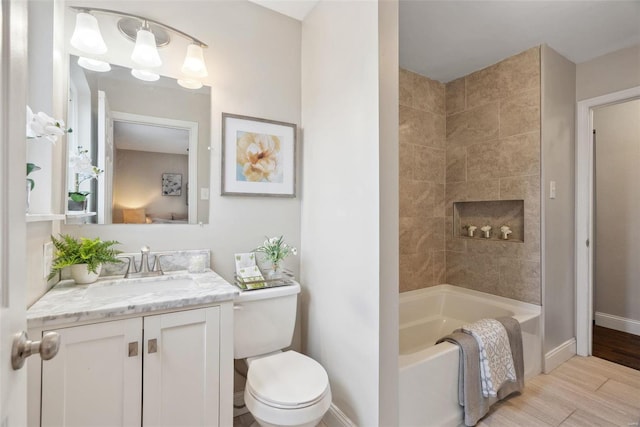 bathroom with toilet, vanity, wood finished floors, a tub, and baseboards