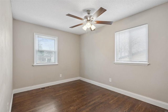 empty room with visible vents, dark wood-type flooring, a ceiling fan, a textured ceiling, and baseboards