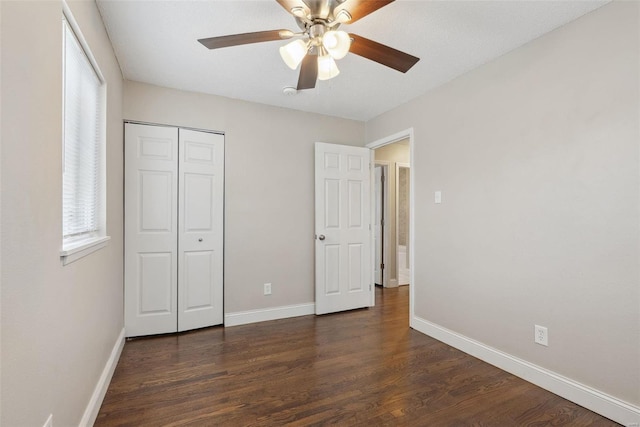 unfurnished bedroom featuring dark wood-style floors, ceiling fan, a closet, and baseboards