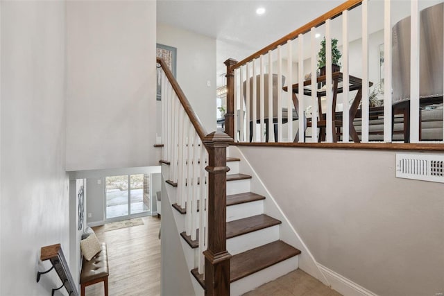 staircase with a high ceiling, wood finished floors, and baseboards