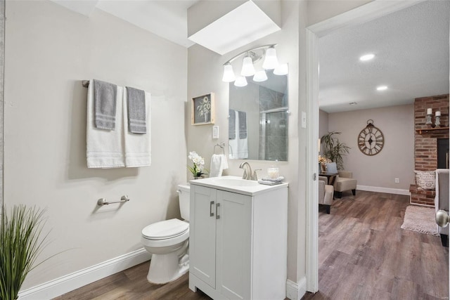 bathroom featuring toilet, a stall shower, vanity, wood finished floors, and baseboards