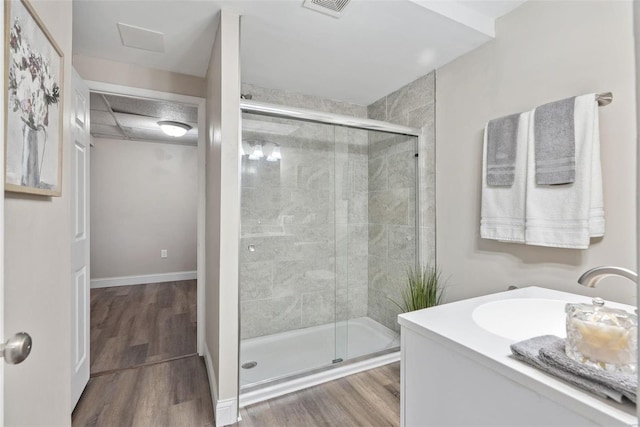 full bathroom with a stall shower, wood finished floors, visible vents, and baseboards