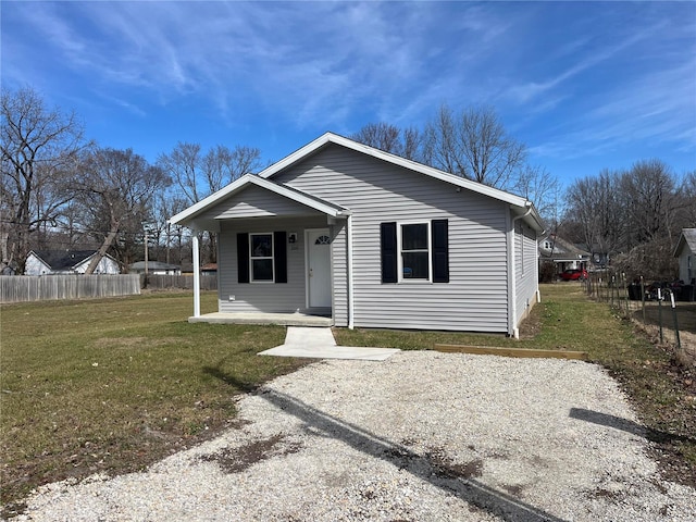 bungalow featuring covered porch, fence, and a front lawn