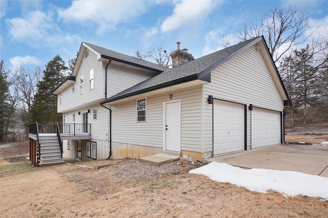 exterior space featuring a garage, driveway, a chimney, stairway, and a wooden deck