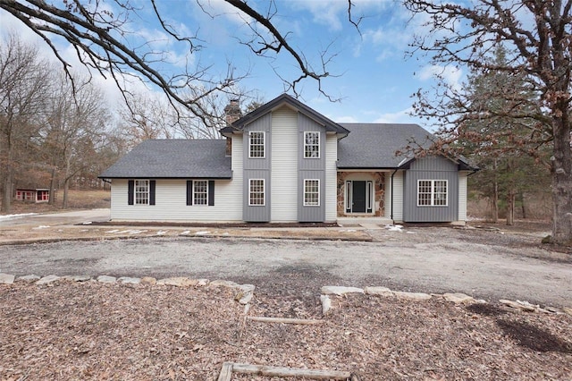 traditional home with a shingled roof and a chimney