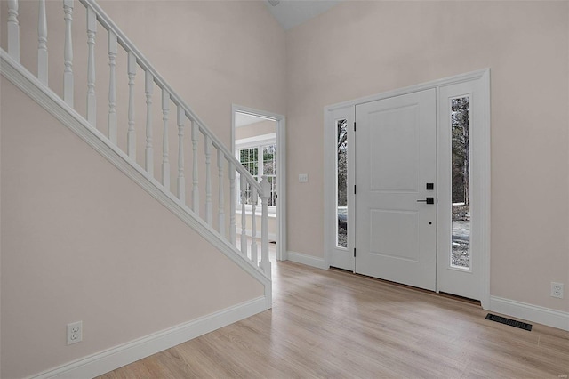 entryway featuring stairs, visible vents, baseboards, and wood finished floors