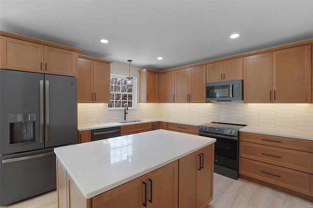 kitchen featuring a sink, hanging light fixtures, appliances with stainless steel finishes, a center island, and tasteful backsplash