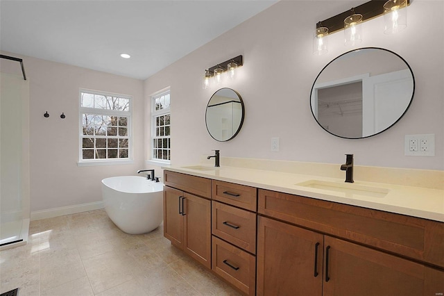 full bathroom with a freestanding bath, double vanity, a sink, and baseboards