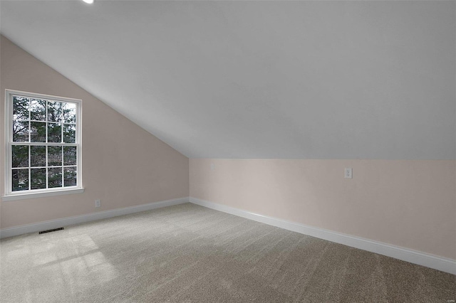 additional living space featuring lofted ceiling, baseboards, visible vents, and carpet flooring