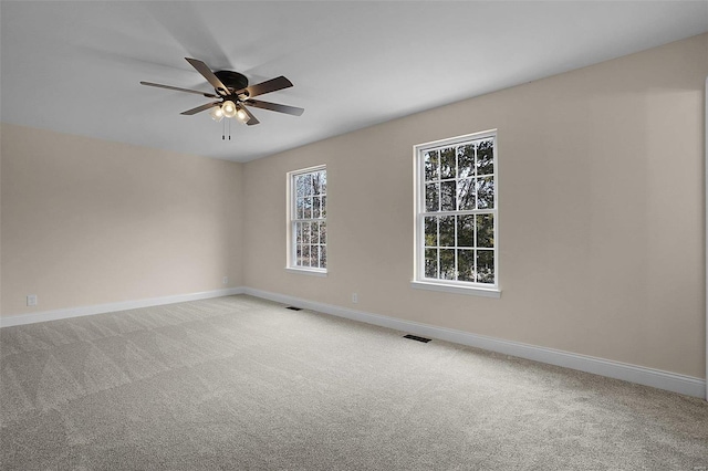 carpeted spare room featuring a ceiling fan, visible vents, and baseboards