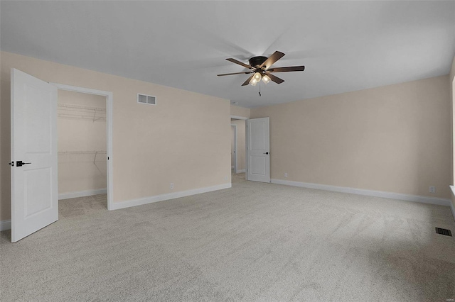 spare room featuring light carpet, ceiling fan, visible vents, and baseboards