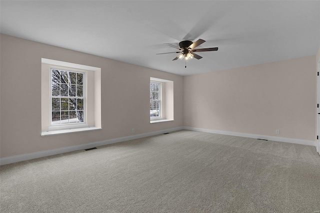 empty room with light carpet, ceiling fan, visible vents, and baseboards