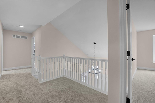 corridor with baseboards, visible vents, a notable chandelier, and carpet flooring