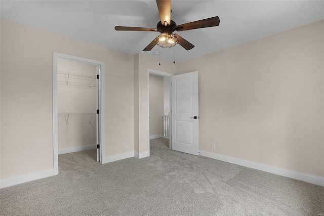 unfurnished bedroom featuring a closet, carpet, a walk in closet, and baseboards