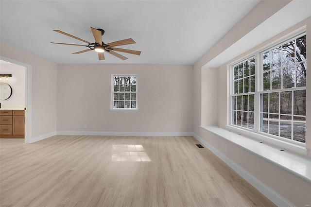 empty room featuring a ceiling fan, light wood-type flooring, visible vents, and baseboards