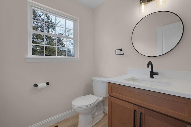 bathroom featuring baseboards, vanity, toilet, and wood finished floors