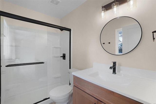 bathroom with a stall shower, visible vents, vanity, and toilet