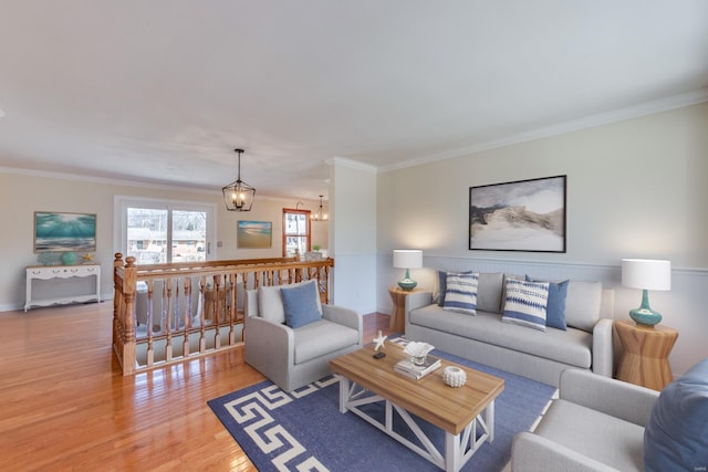 living area with light wood-style floors, crown molding, and a notable chandelier