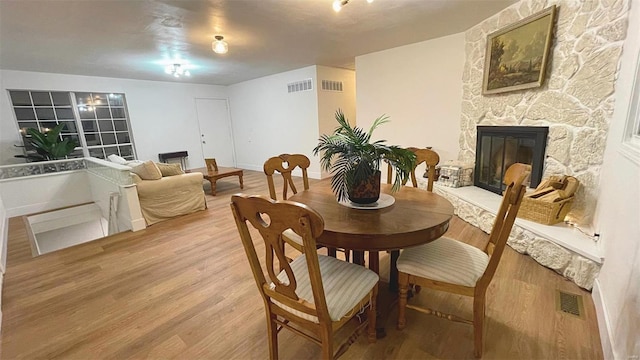 dining space featuring visible vents, a fireplace, and light wood-style flooring